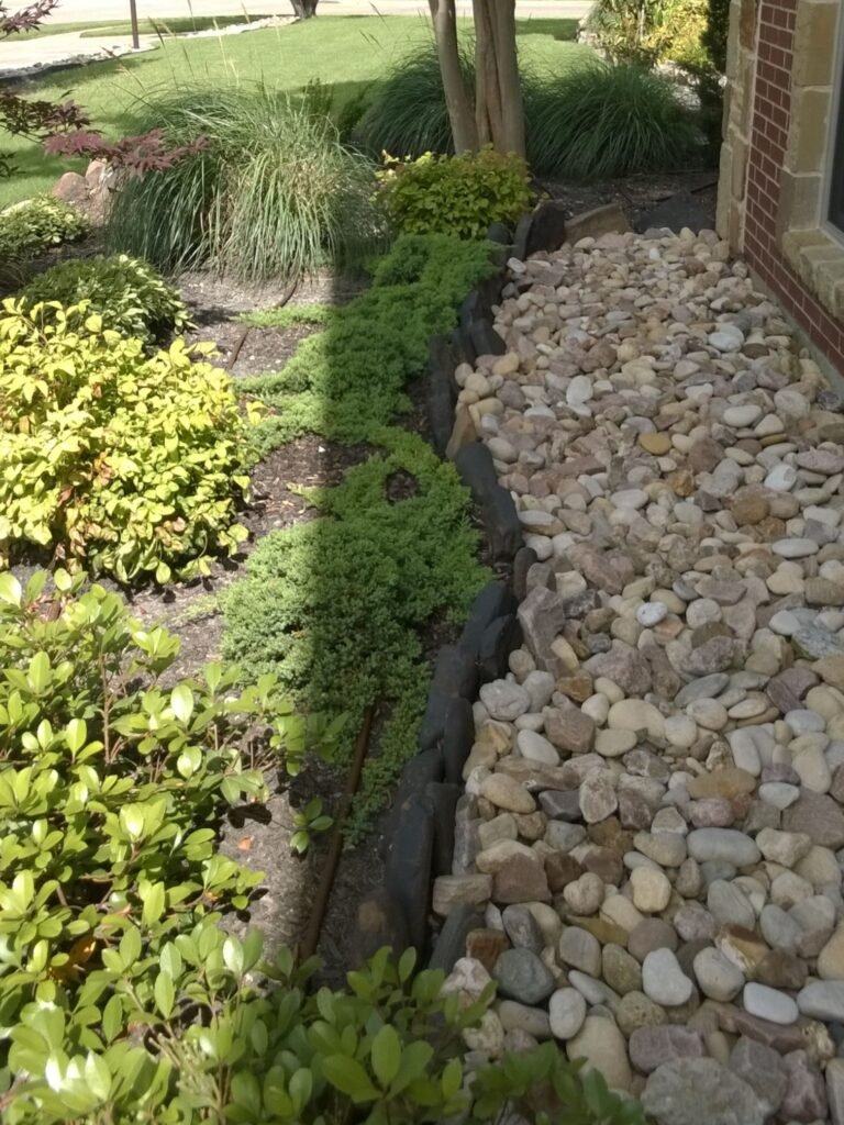 DIY frontyard landscape showing rock beds in front of plant beds