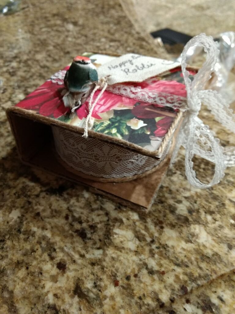 A different angle of finished DIY gift wrap. A white lace ribbon keeps the hinged lid close over the round cardboard ring