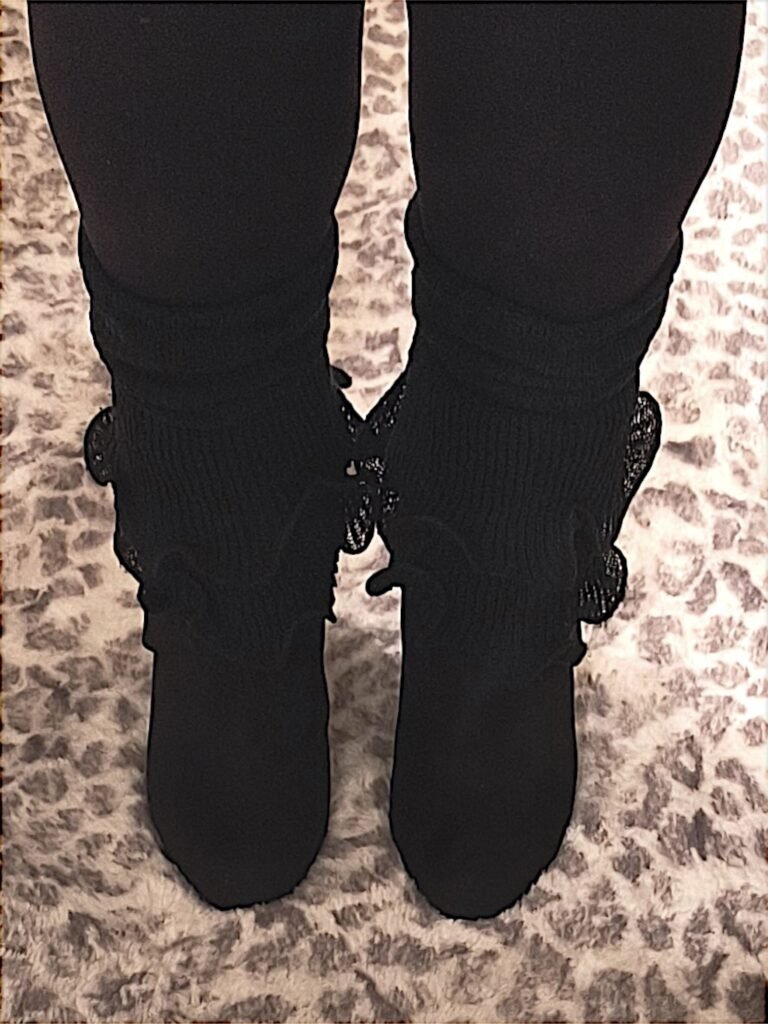 closeup of woman's legs wearing black leggings, ruffled black leg warmers and black shoes