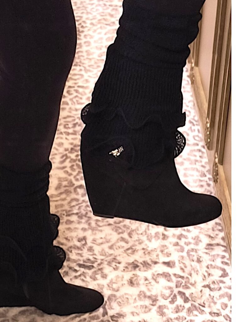 profile of woman's legs wearing black leggings, ruffled black leg warmers and black wedge boots