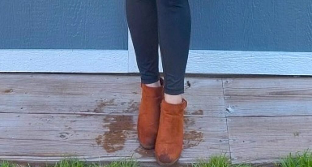 an unattractive gap appears where the woman's blue leggings end and the top of her cognac colored ankle boots begins.