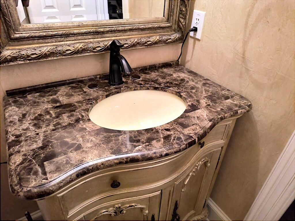 Small marble bathroom vanity counter prior to updates with metallic foil